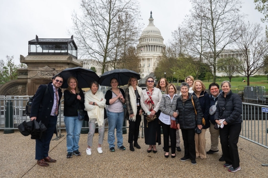 people smiling and standing in front of umbrellas at the US Capitol Building