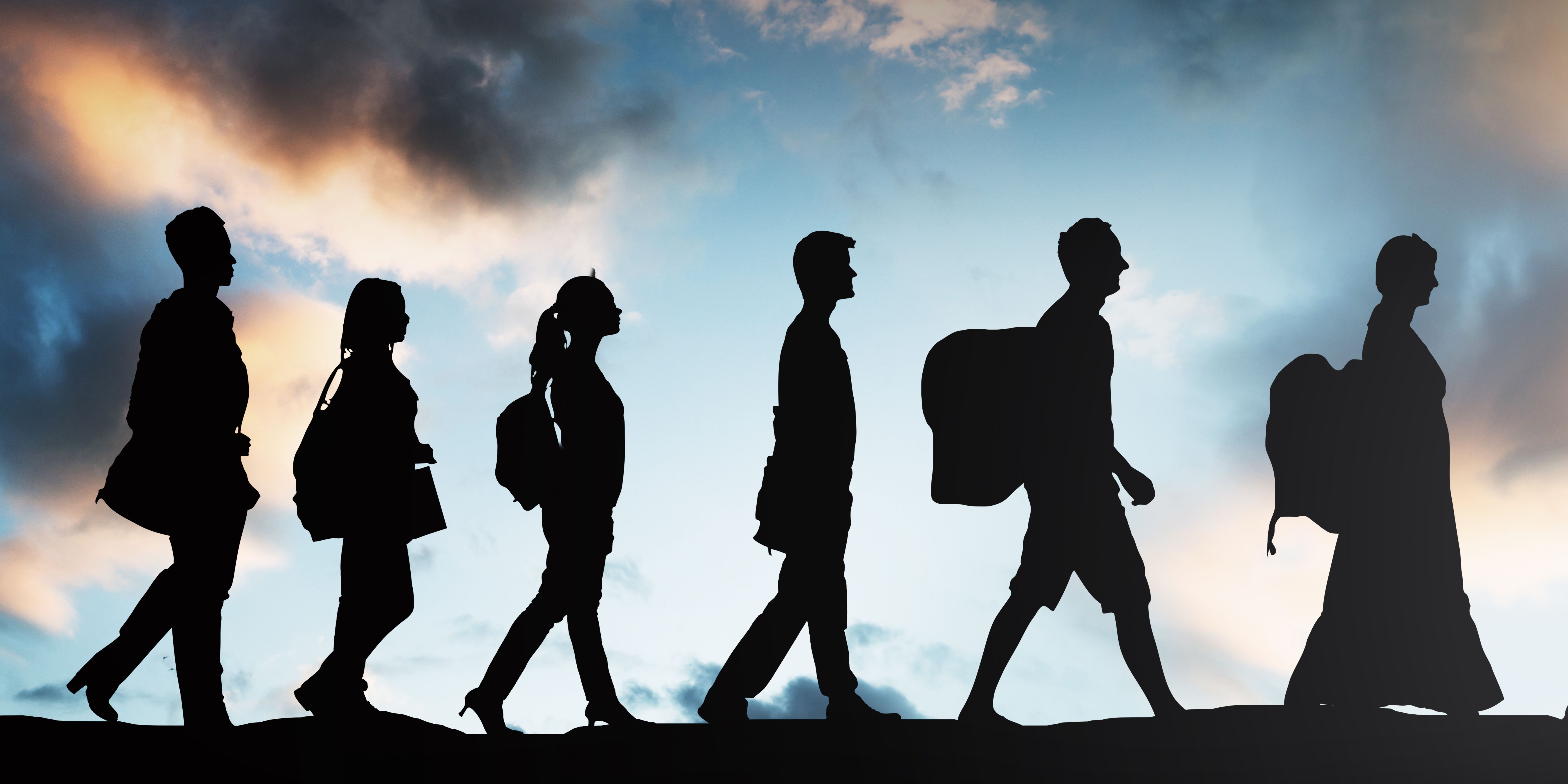 six silhouetted people walking with clouds behind them 