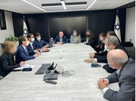 Men and women around a table. Women's faces are blurred by an Ultra-Orthodox internet news site.