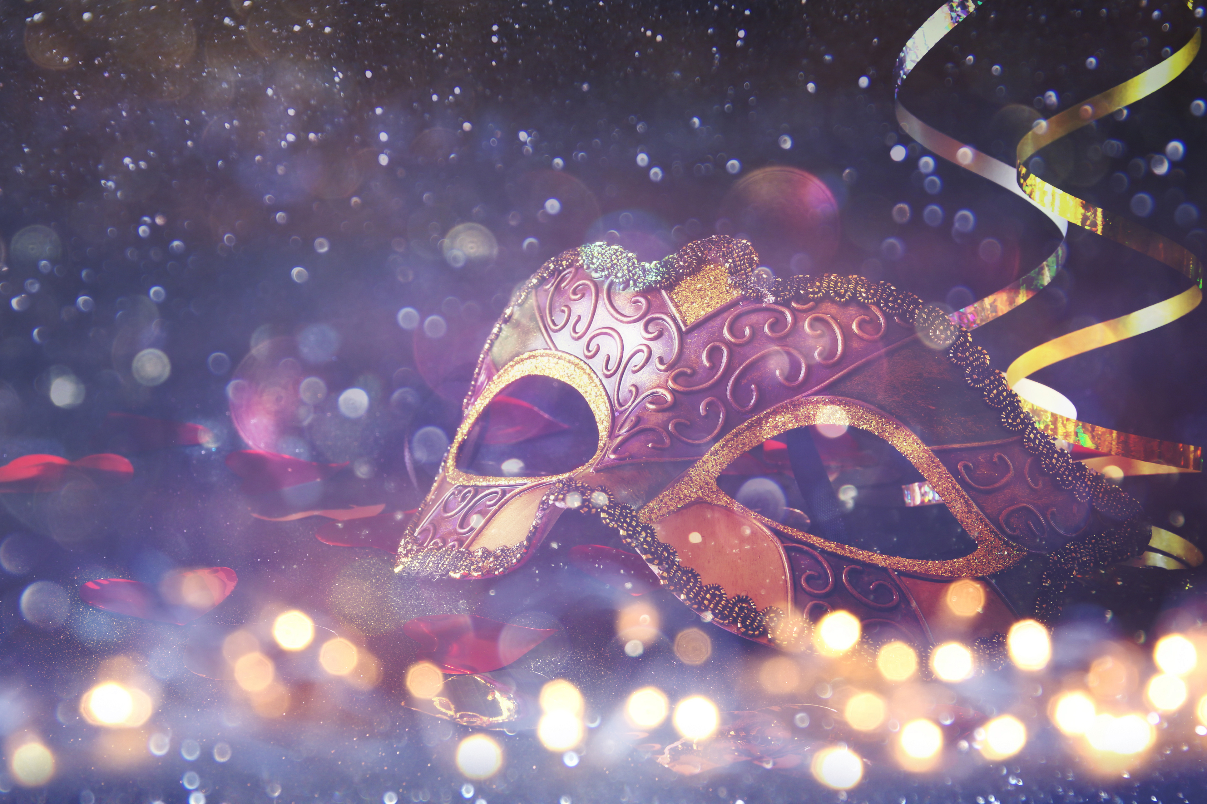 A mask with gold ribbons and purple and gold glitter