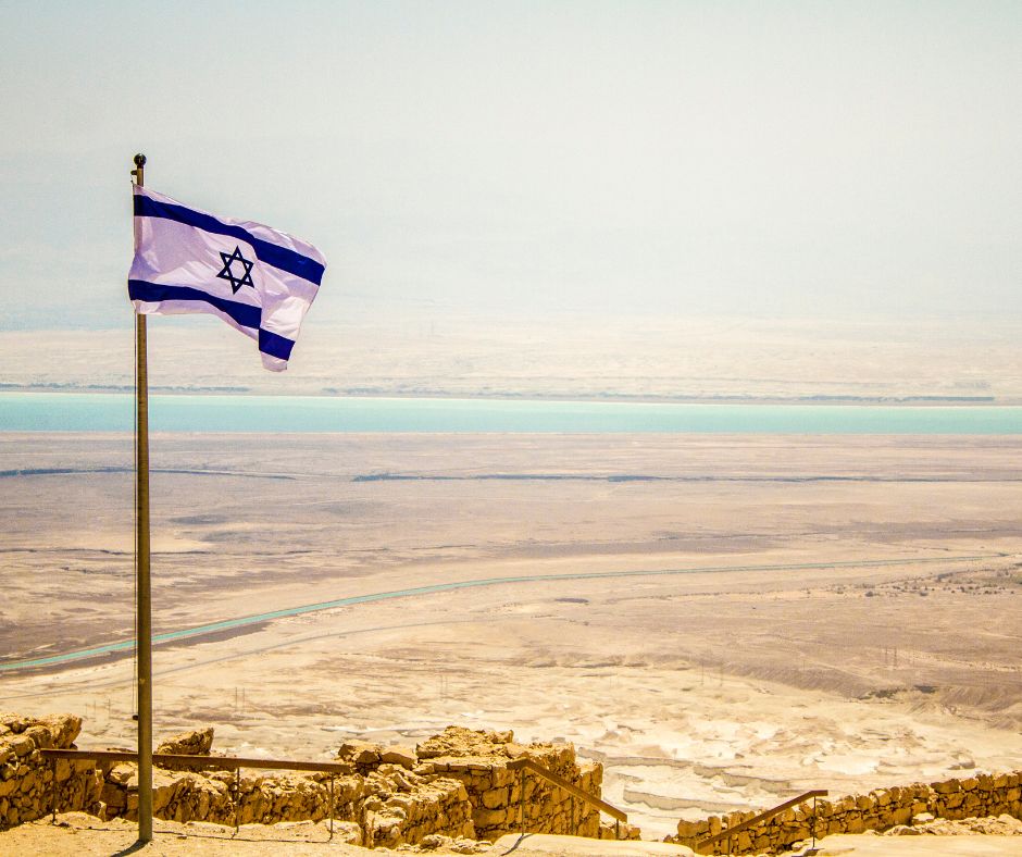 An Israel flag mounted in a desert/vista. 