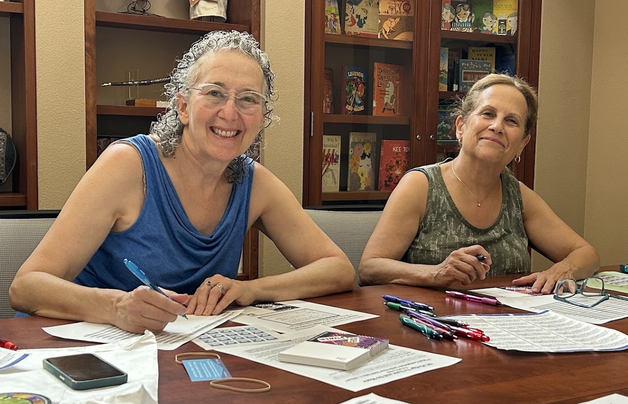 two women from Congregation B'nai Israel filling out post cards to influence Florida voters to vote in the 2024 election