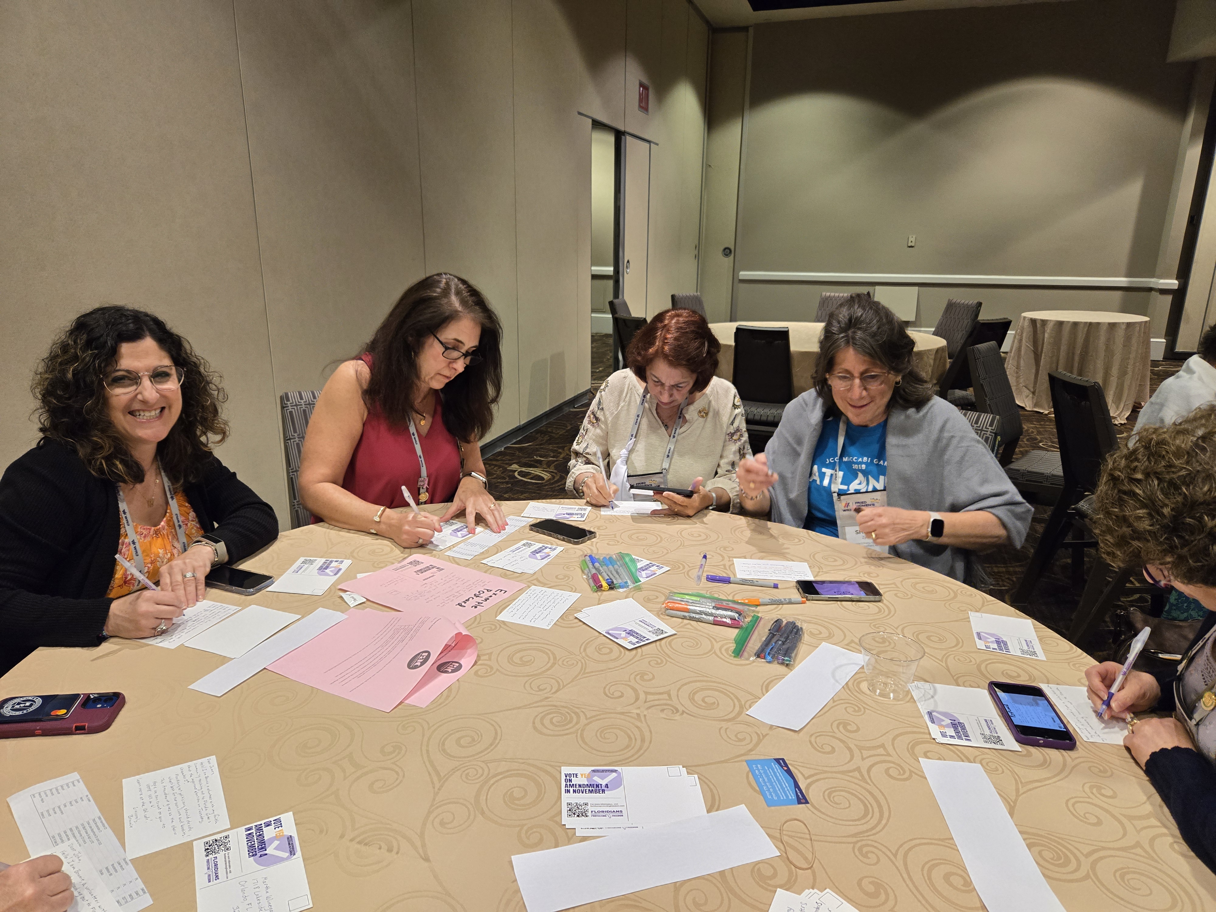 women sitting around table writing postcards