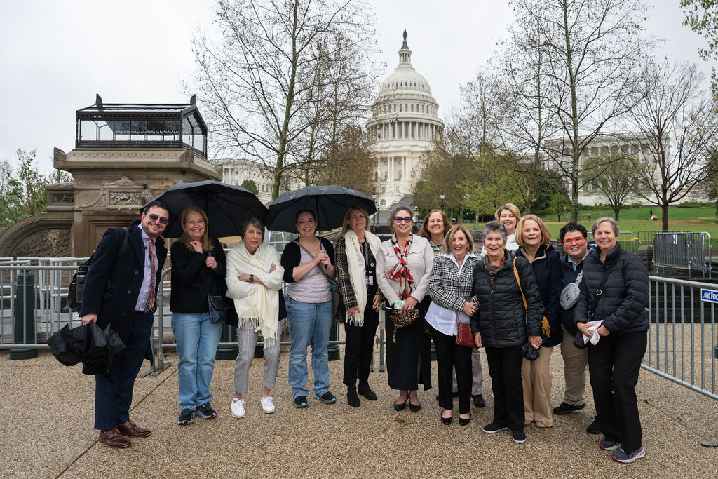 people smiling and standing in front of umbrellas at the US Capitol Building