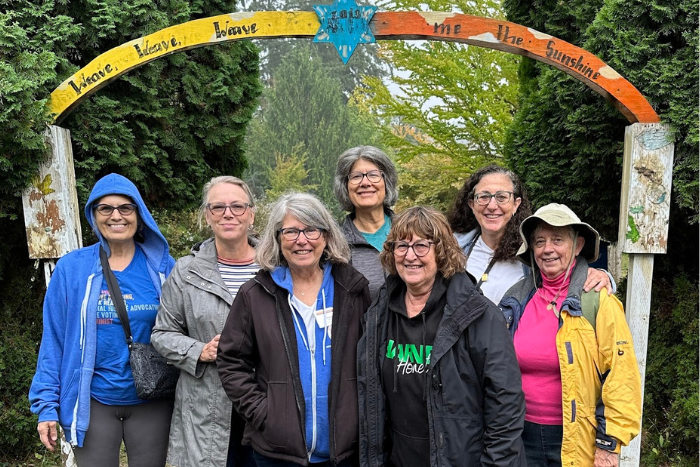 women smiling in front of colorful, painted arch that says "weave, weave, weave me into sunshine"
