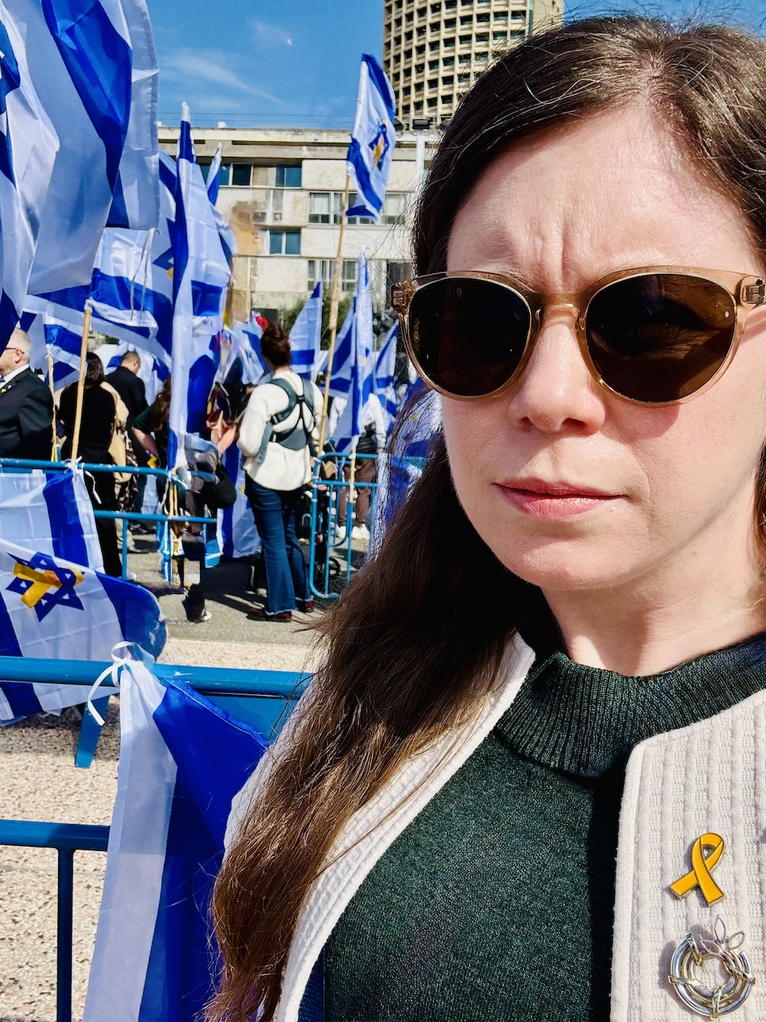 Liz standing with Israeli flags in the background