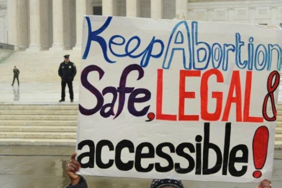 woman holding sign in front of supreme court about legal abortion