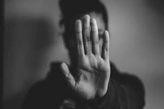 A black and white photo of a woman holding her hand up in protest