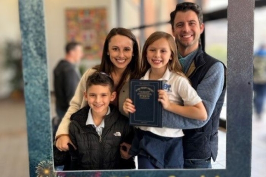 Mandee Heinl and her family smiling in a life-size photo frame. 