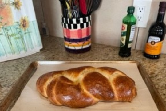 A challah on a baking tray on a kitchen counter.