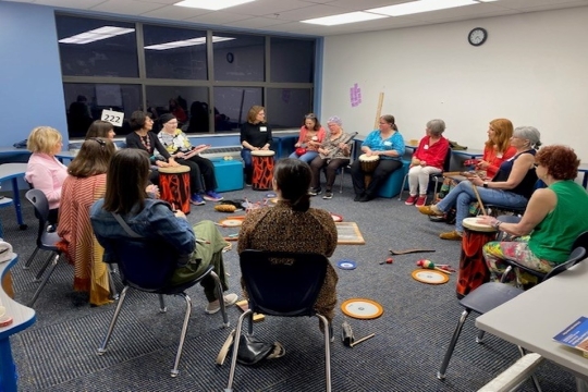 women sitting in a circle playing drums and other percussion instruments