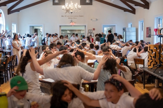 children at camp putting hands on each other's heads in prayer