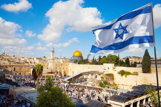 A view of the Western Wall with an Israeli flag blowing in the wind