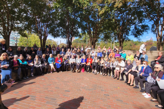 a group of women sitting outside at a park on some benches