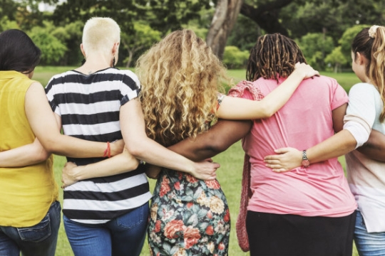 Women of varying races from the back linking arms and marching in solidarity