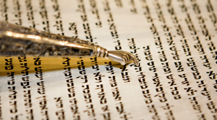 Silver yad pointing to Hebrew text in Torah scroll